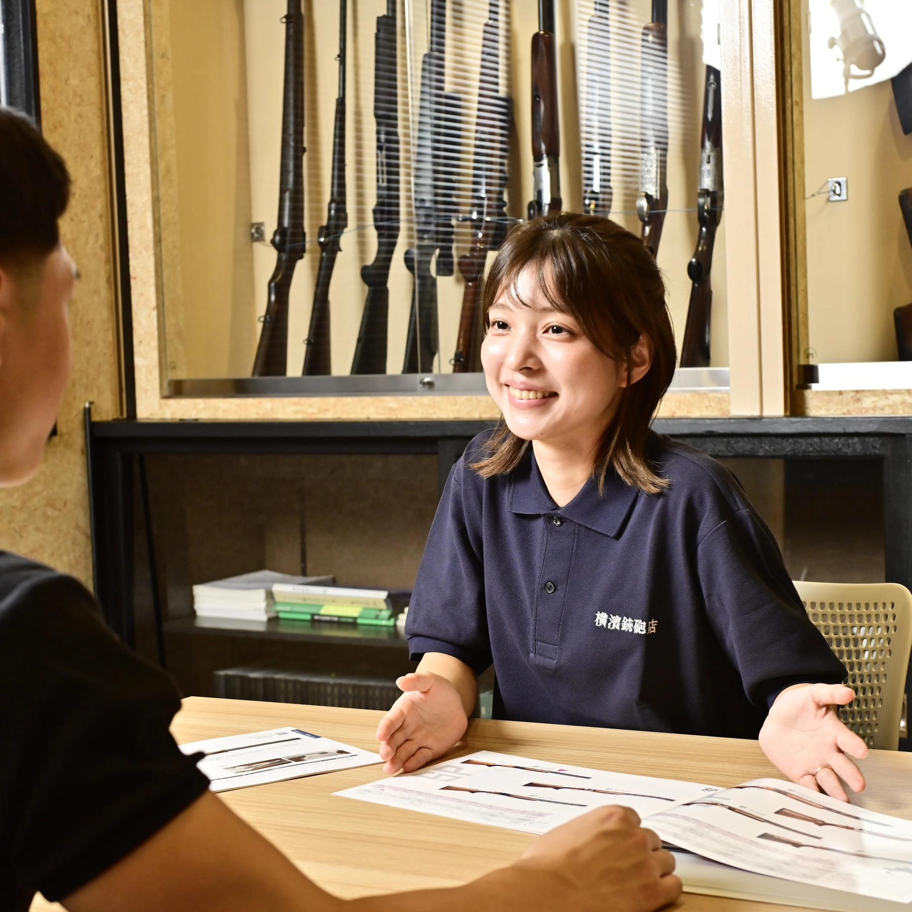 スタッフが笑顔で猟銃所持許可の手続き相談を受ける様子